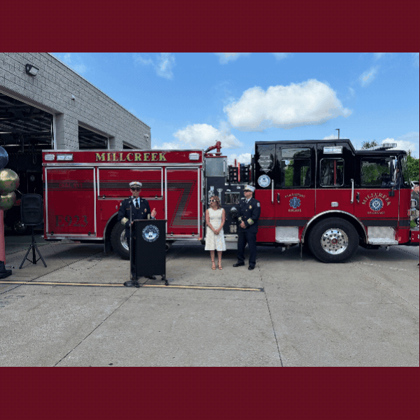 Slideshow of photos of firefighters speaking at podium and pushing fire engine into station.